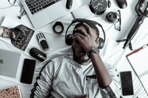 Man being overwhelmed by tech gadgets