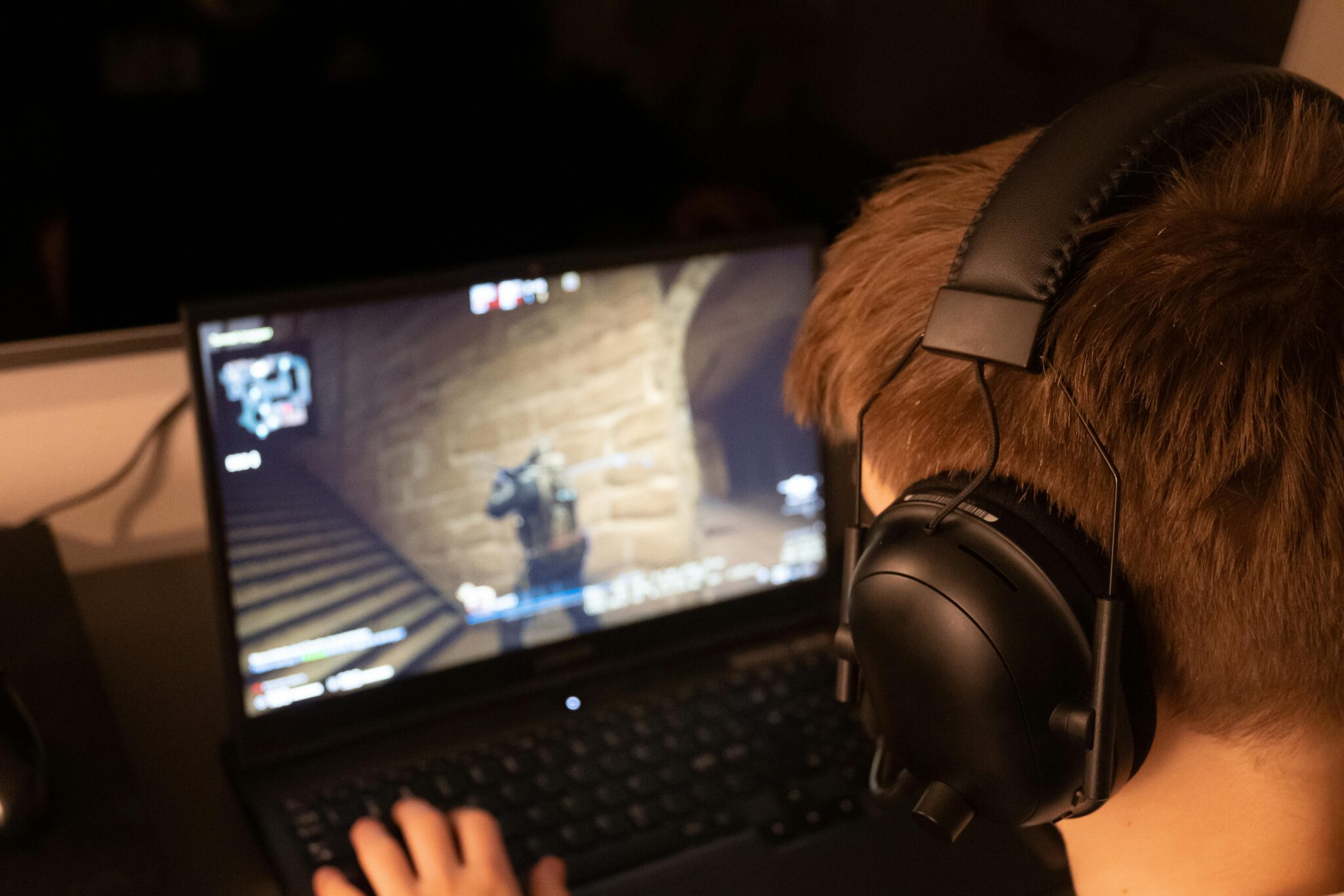 a person wearing headphones and using a budget gaming laptop to play games with a dedicated graphics card